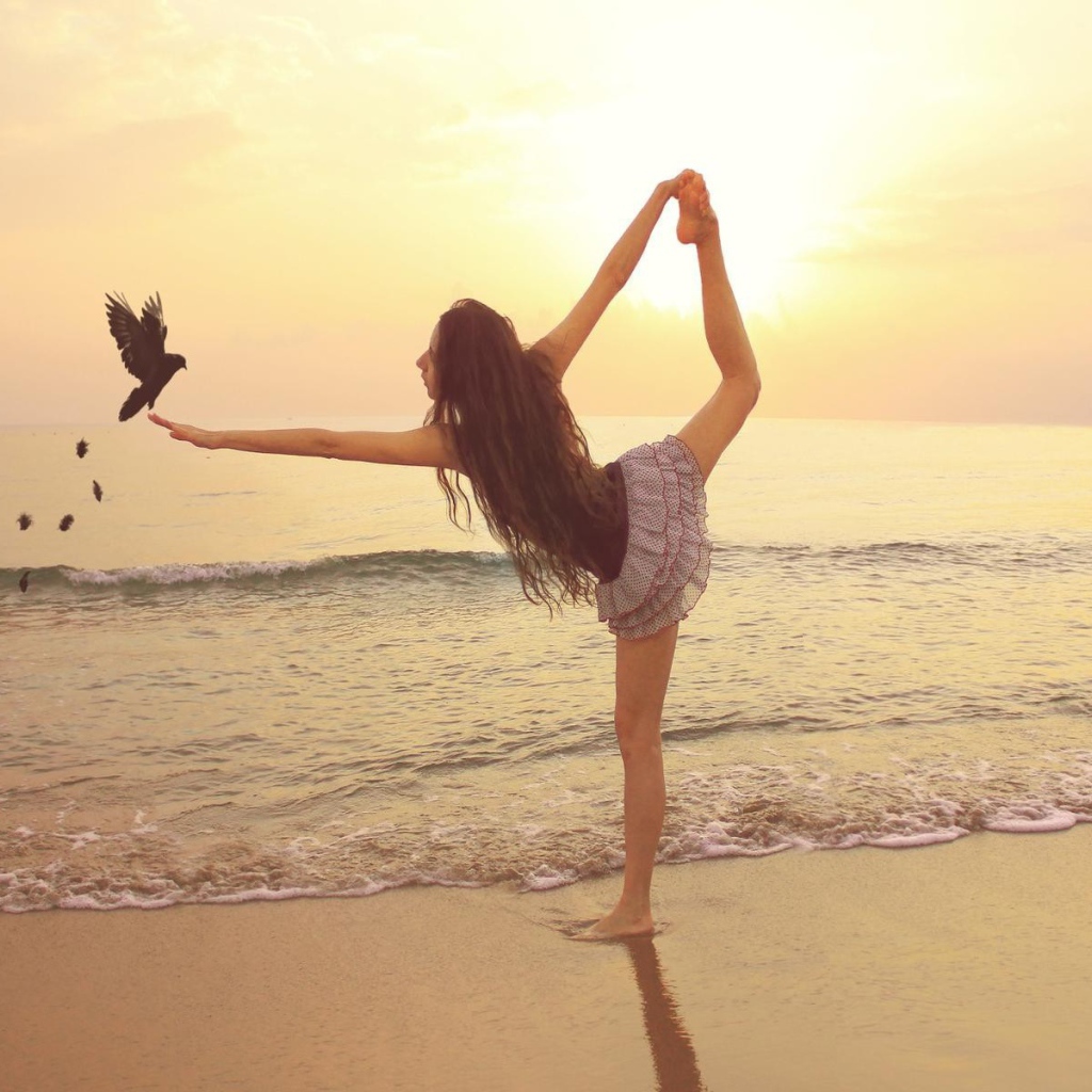 Балерина на берегу моря с птицей