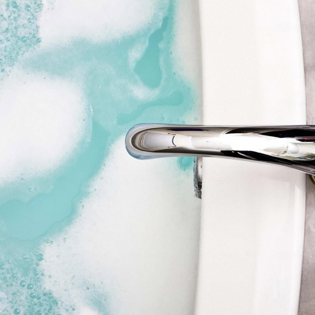 Кран над ванной с голубой водой