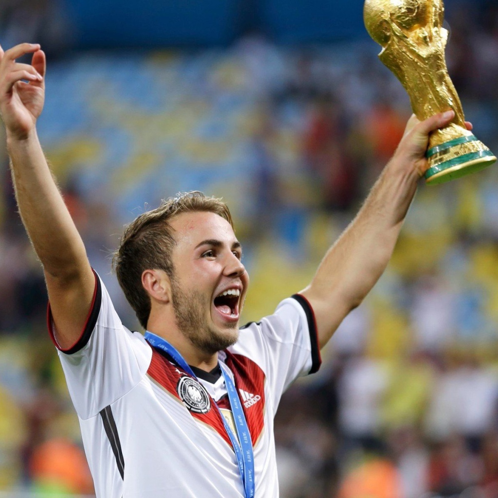 Немецкий футболист Марио Гётце держит в руке кубок