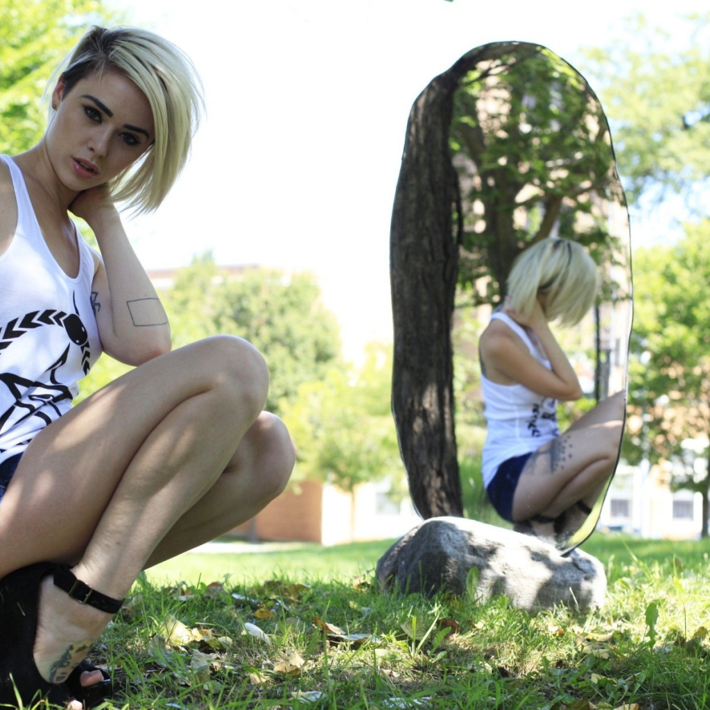 Девушка с тату на природе у зеркала