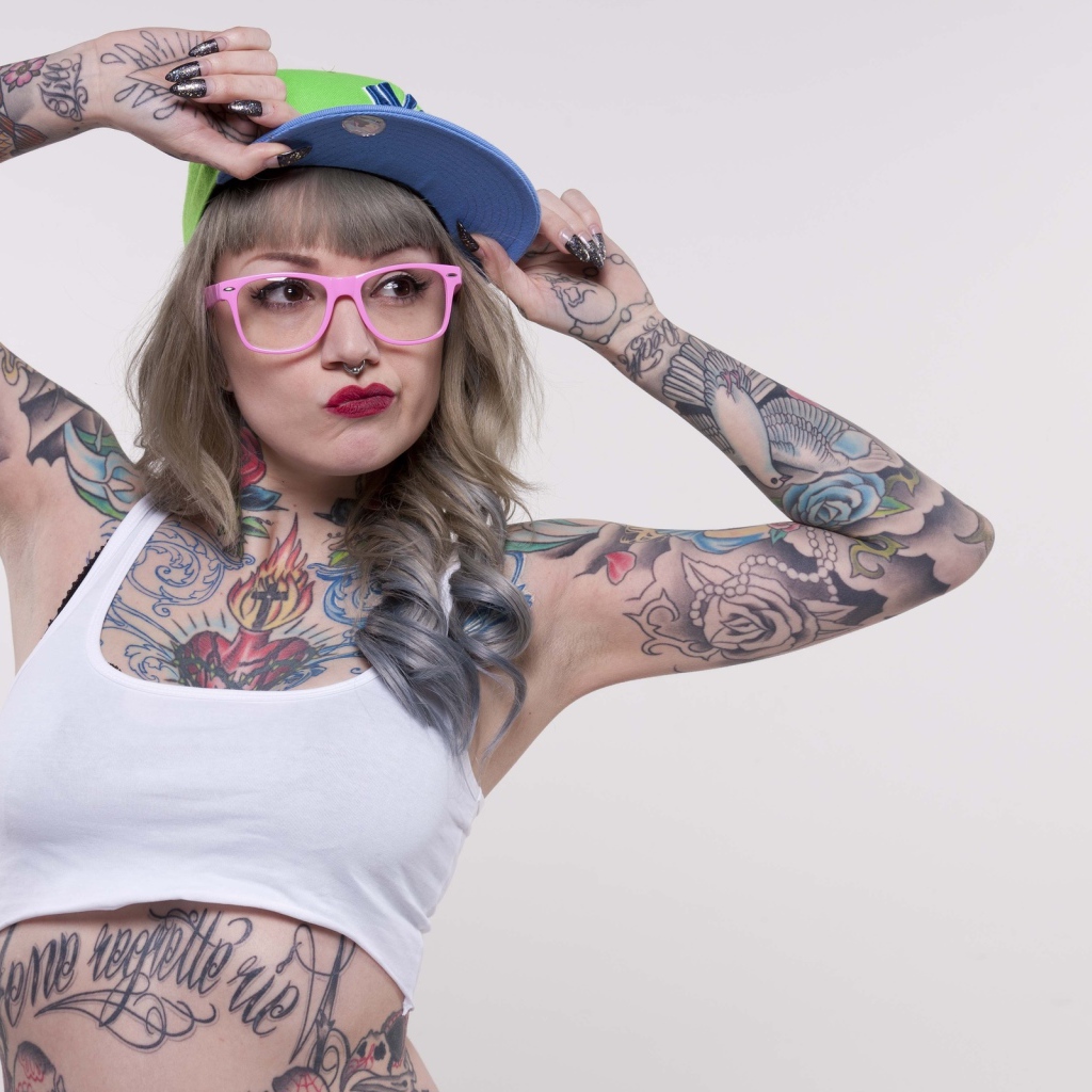 Tattooed woman in a cap and pink glasses