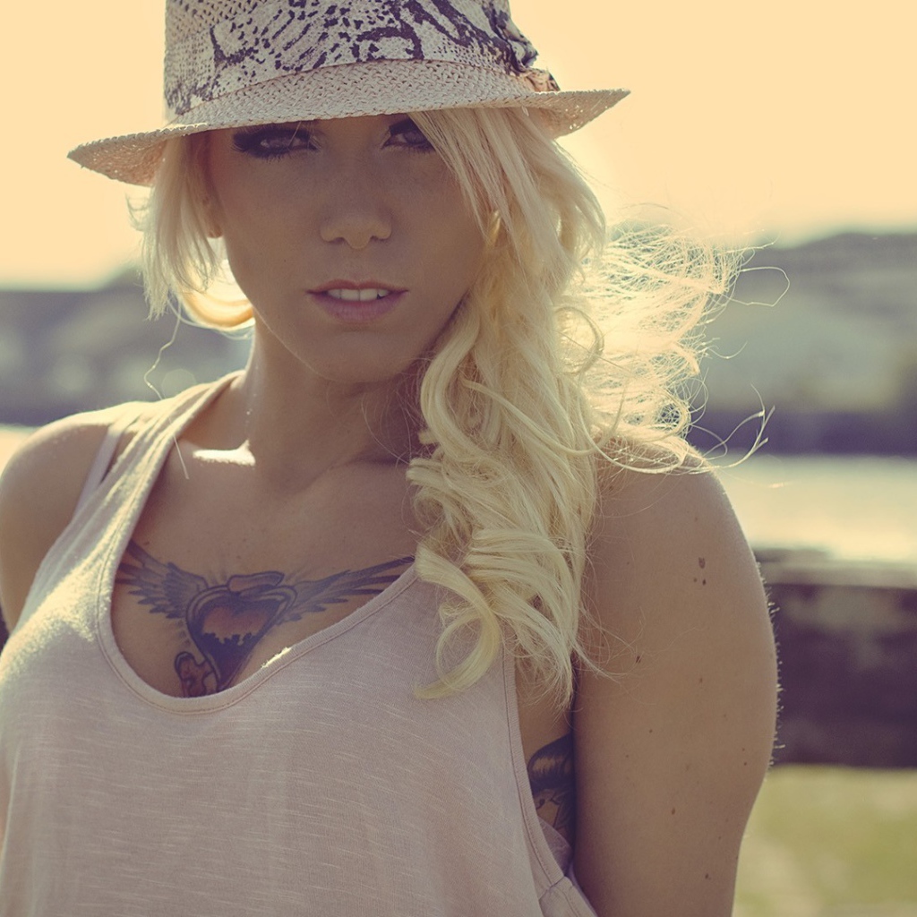 Блондинка в белой шляпе с тату на груди