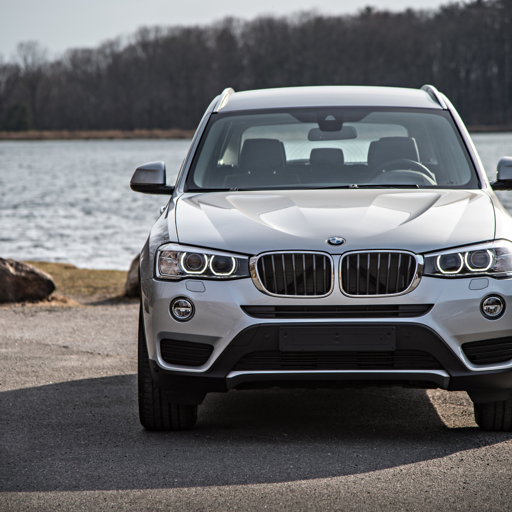 Серебристый автомобиль BMW X3 у водоема 