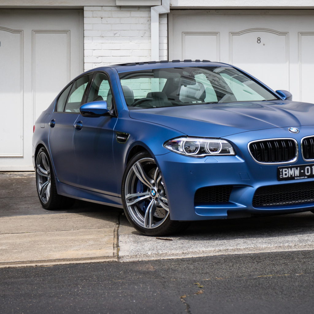 Синий автомобиль BMW 5 Series у гаража