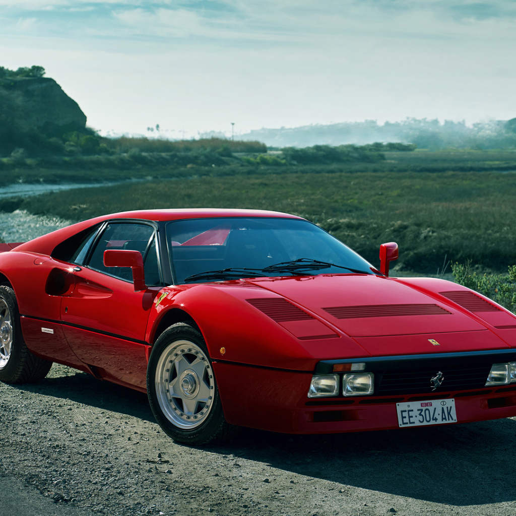 Красный быстрый автомобиль Ferrari 288 GTO у реки