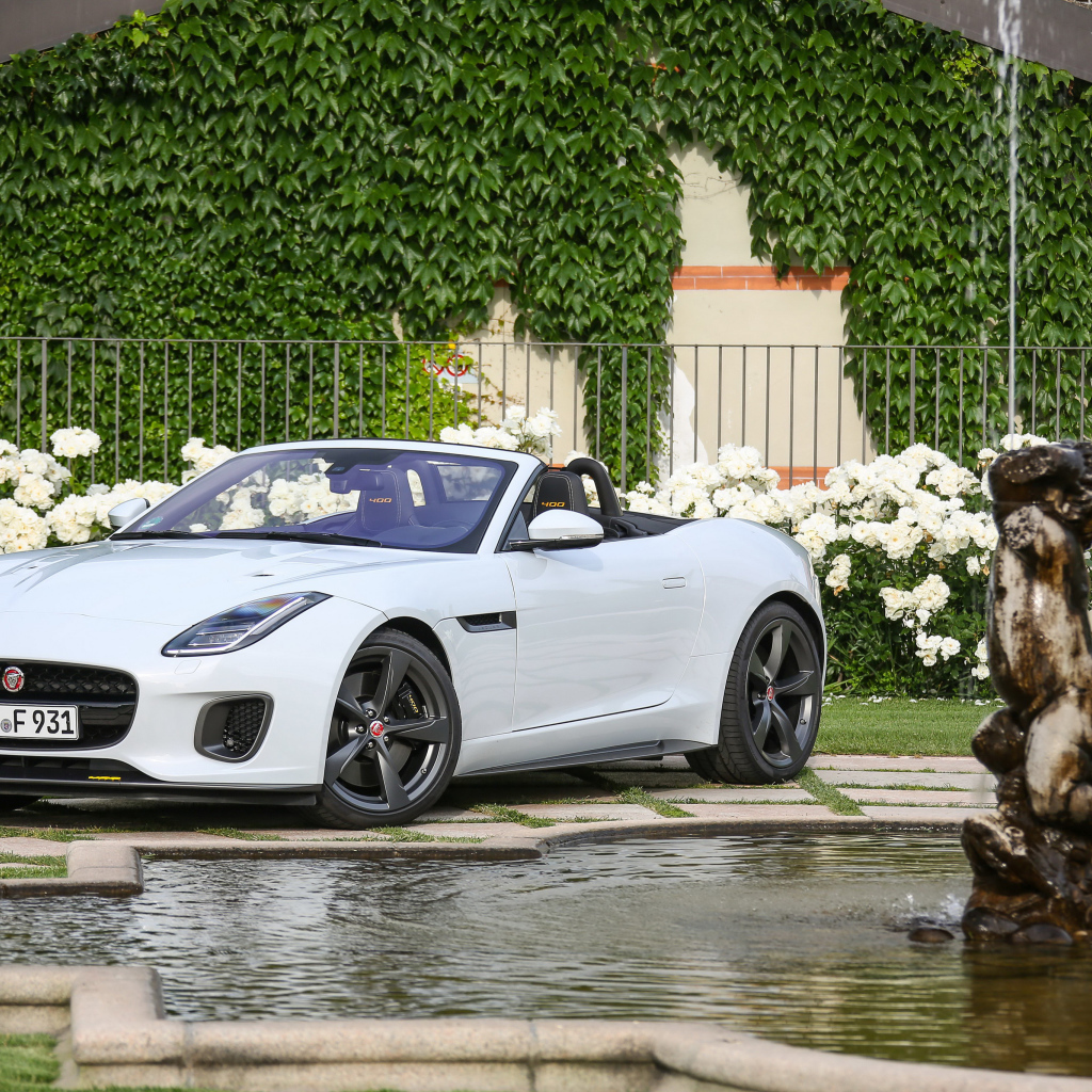 Белый автомобиль кабриолет Jaguar F-Type у фонтана