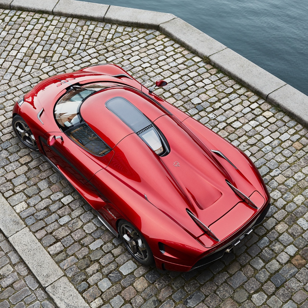 Красный спортивный автомобиль Koenigsegg Regera у воды, вид сверху