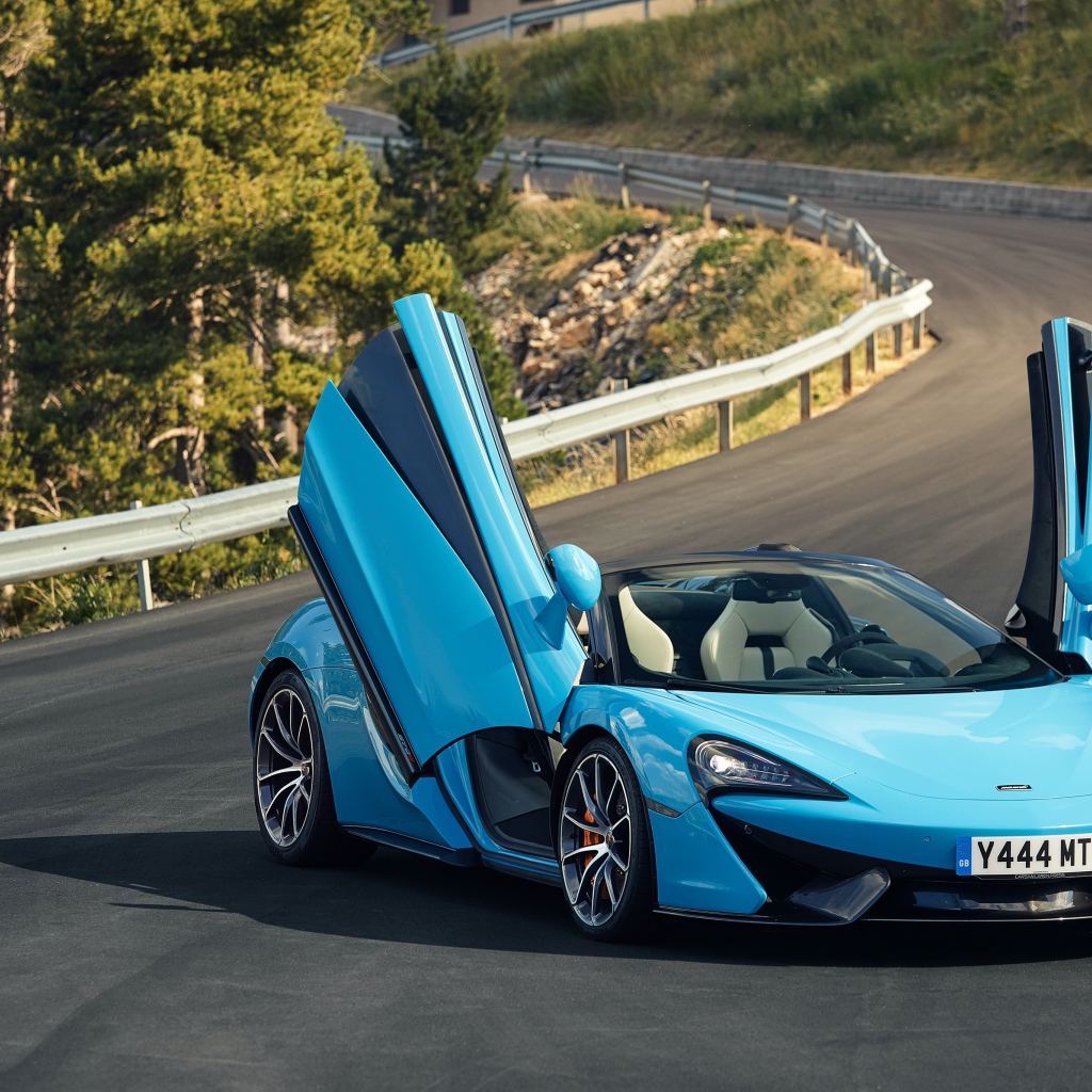 Синий спортивный автомобиль McLaren 570S на трассе с открытыми дверями
