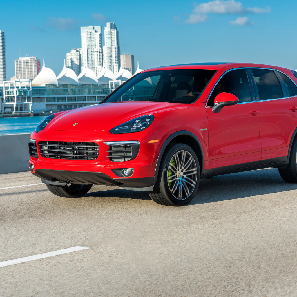 Красный автомобиль Porsche Cayenne на фоне города 