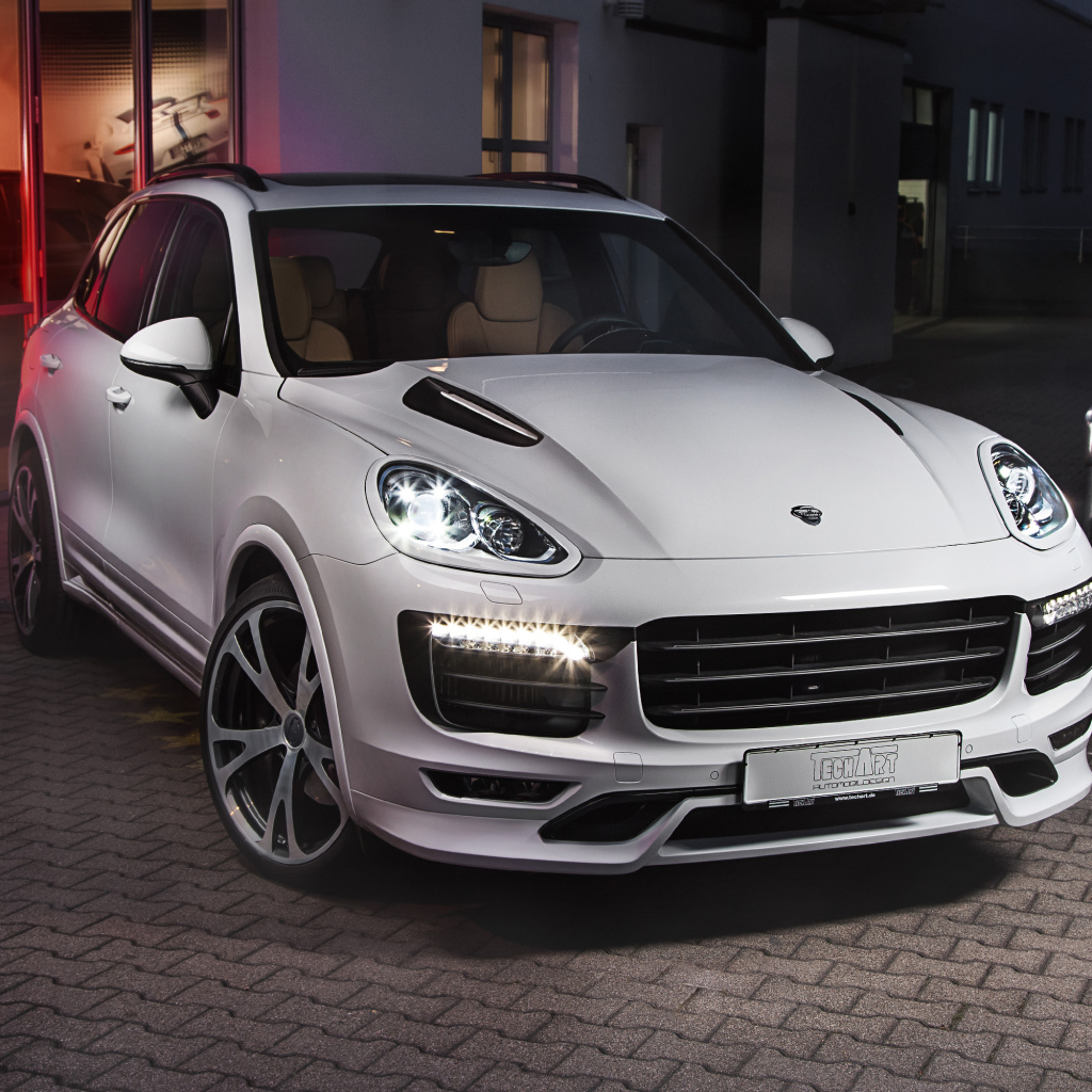 Белый внедорожник Porsche Cayenne с включенными фарами