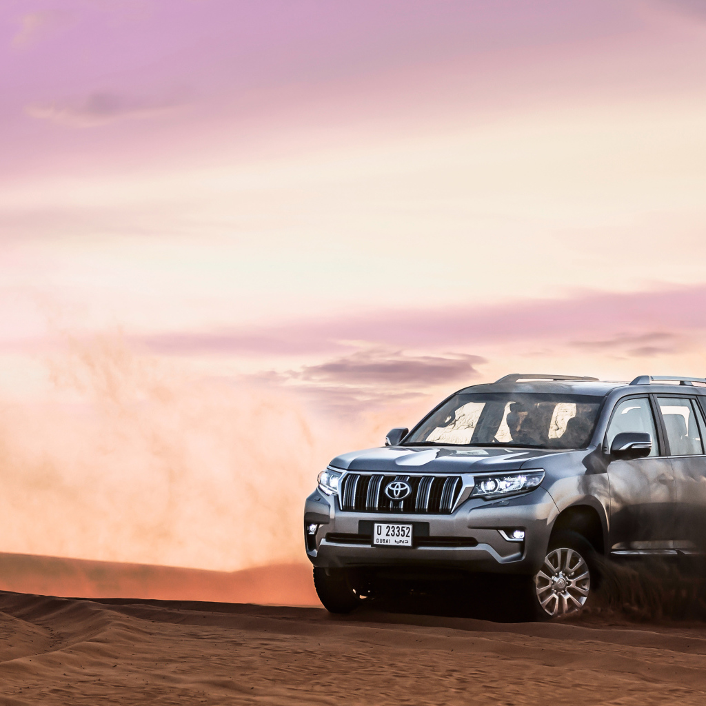 Серебристый внедорожник Toyota Land Cruiser Prado, 2018 едет по песку