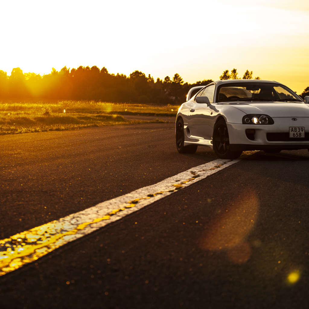 Белый автомобиль Toyota Supra стоит на трассе на рассвете