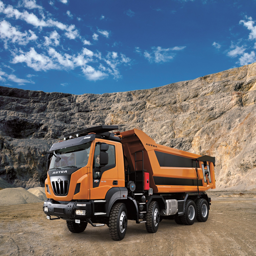 Оранжевый грузовик Astra HD9 84.50 8×4 в карьере под голубым небом