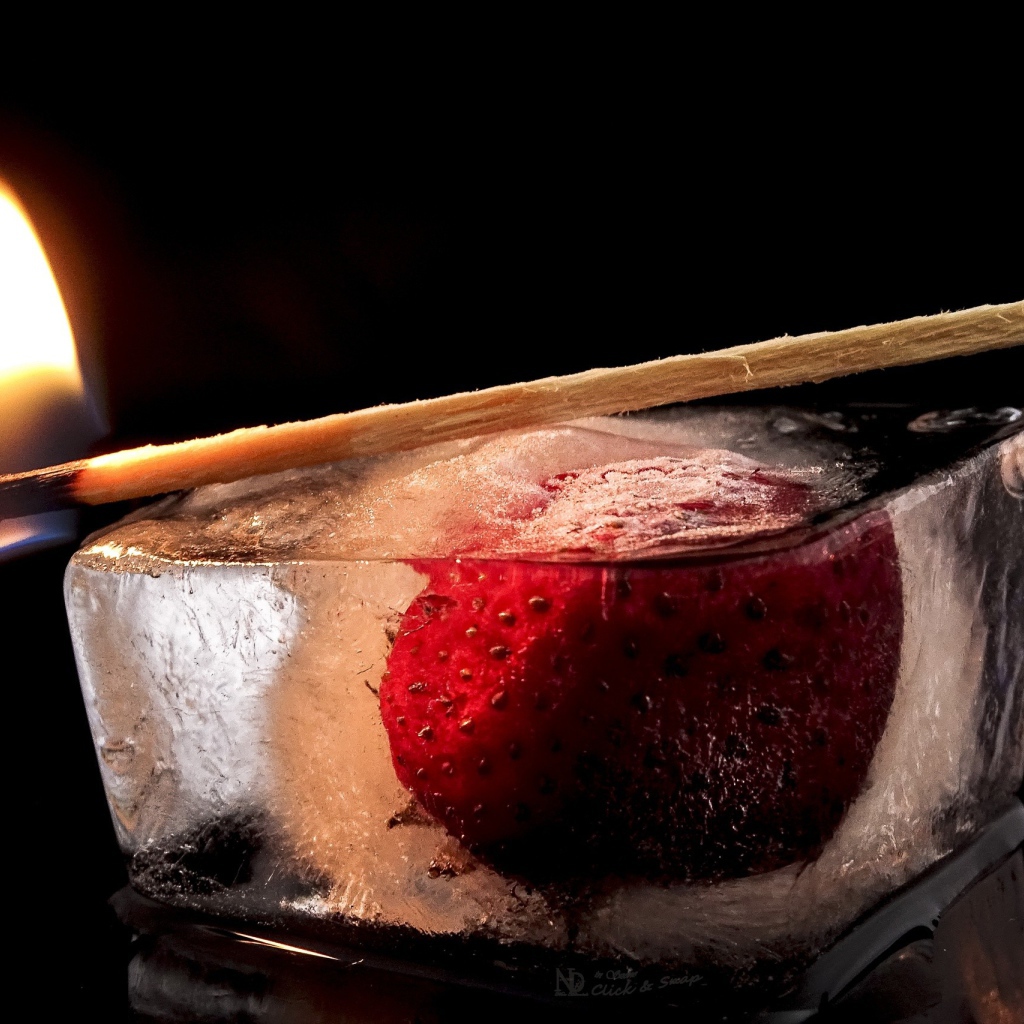 Зажженная спичка на кусочке льда с клубникой 