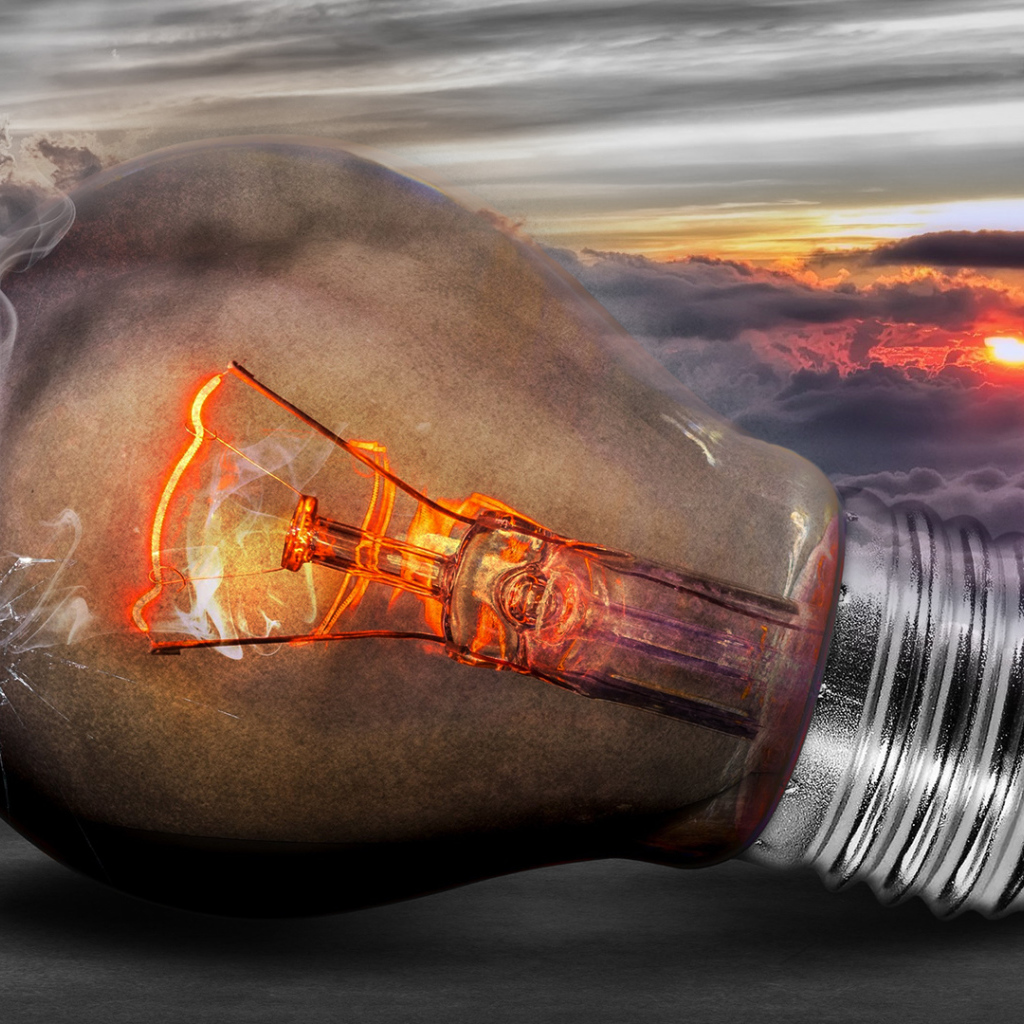 Раскаленная лампочка на фоне белых облаков в небе