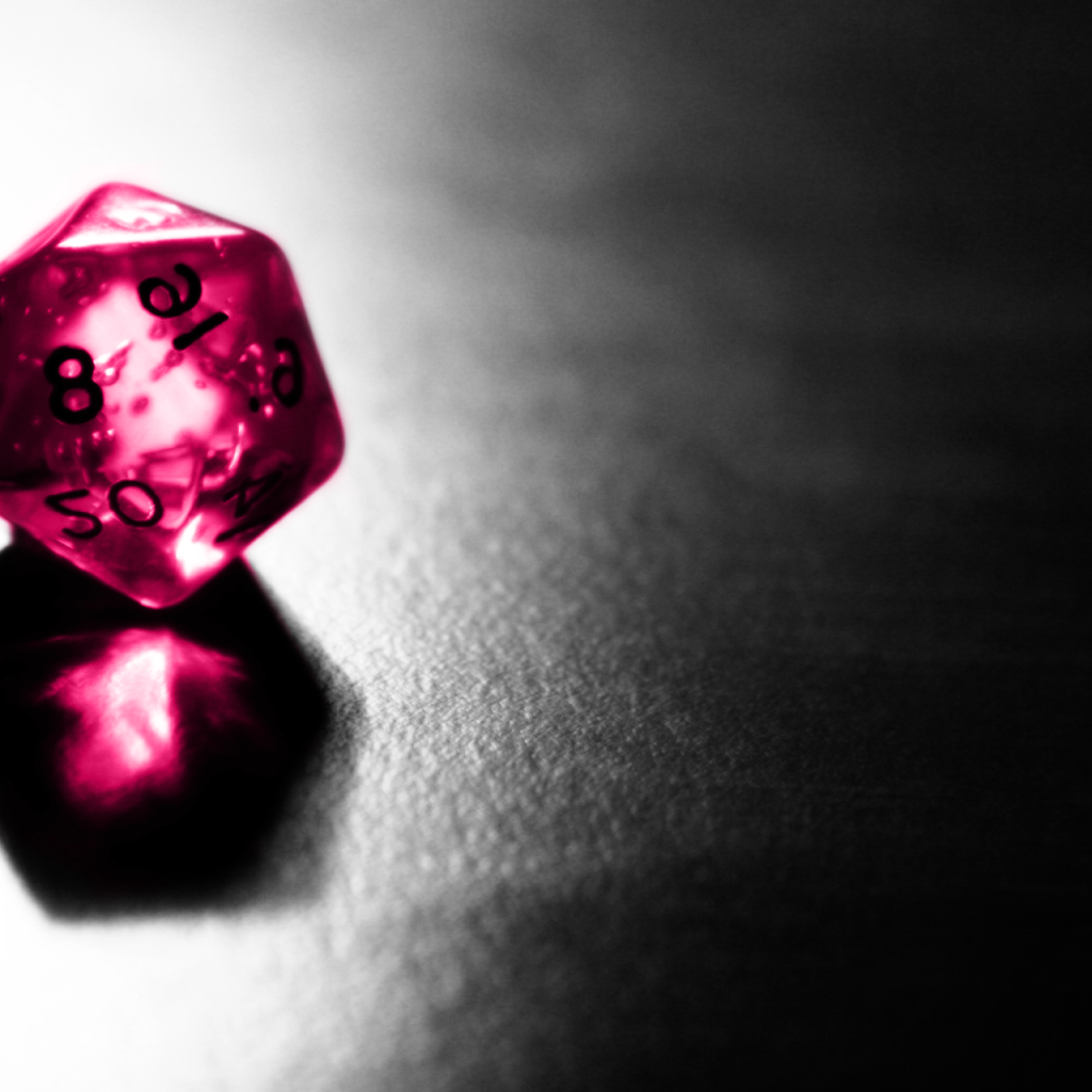 Розовый фигурный кубик отражается серой поверхности стола