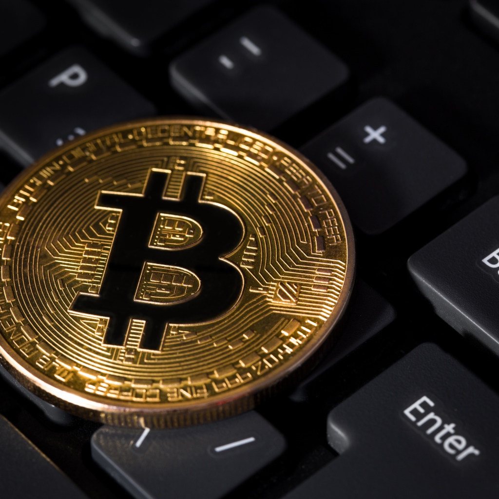Монета биткоин лежит на черной клавиатуре