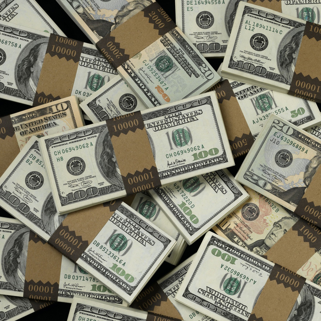 Много пачек купюр по сто долларов
