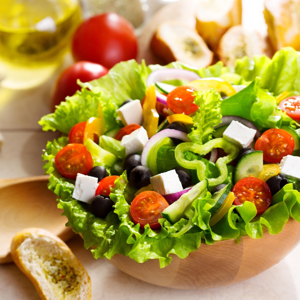 Аппетитный Греческий салат на тарелке с листьями салата