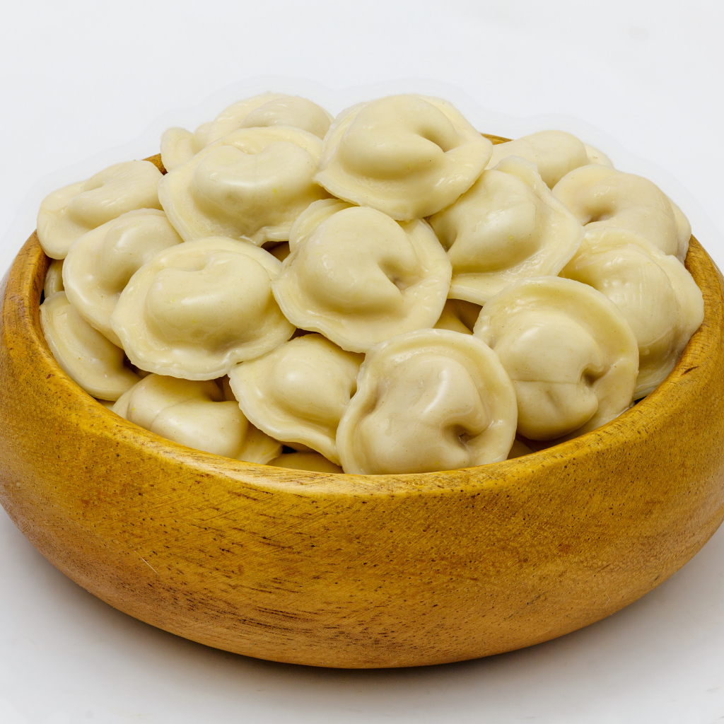 Аппетитные пельмени в деревянной миске на сером фоне