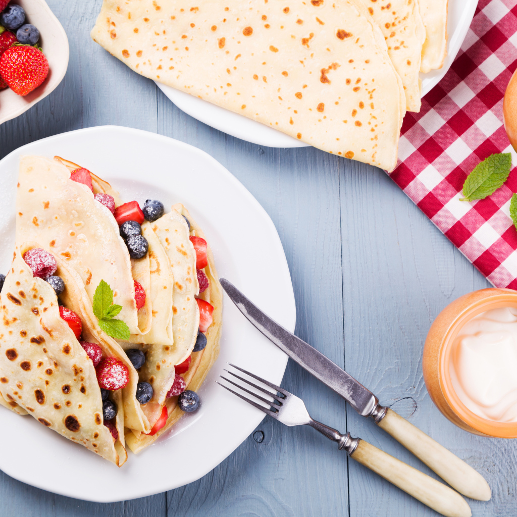 Аппетитные блинчики с ягодами на белой тарелке 