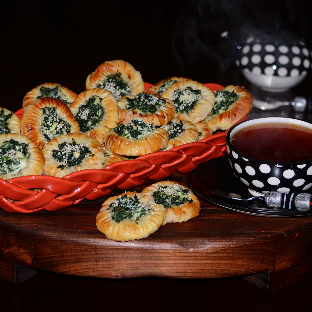 Булочки с зеленью и горячим чаем на черном фоне