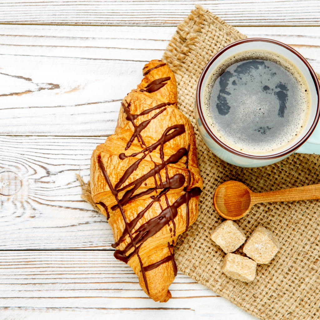 Круассан с шоколадом и чашкой кофе на столе