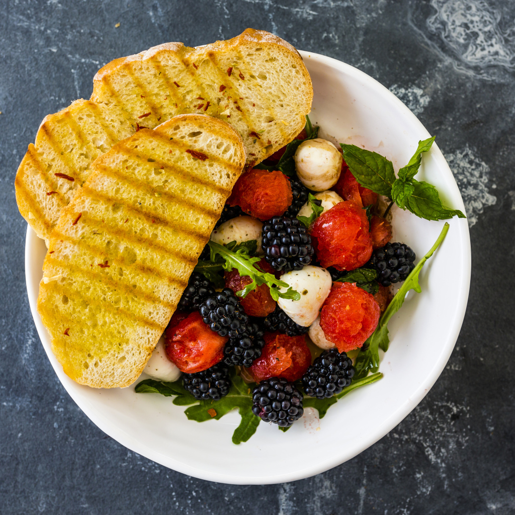 Гренки с салатом из ягод на белой тарелке