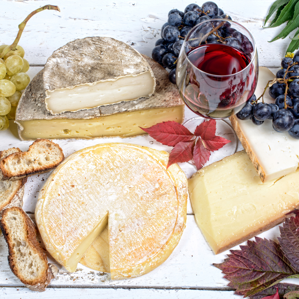 Дорогой сыр с плесенью на столе с виноградом и красным вином