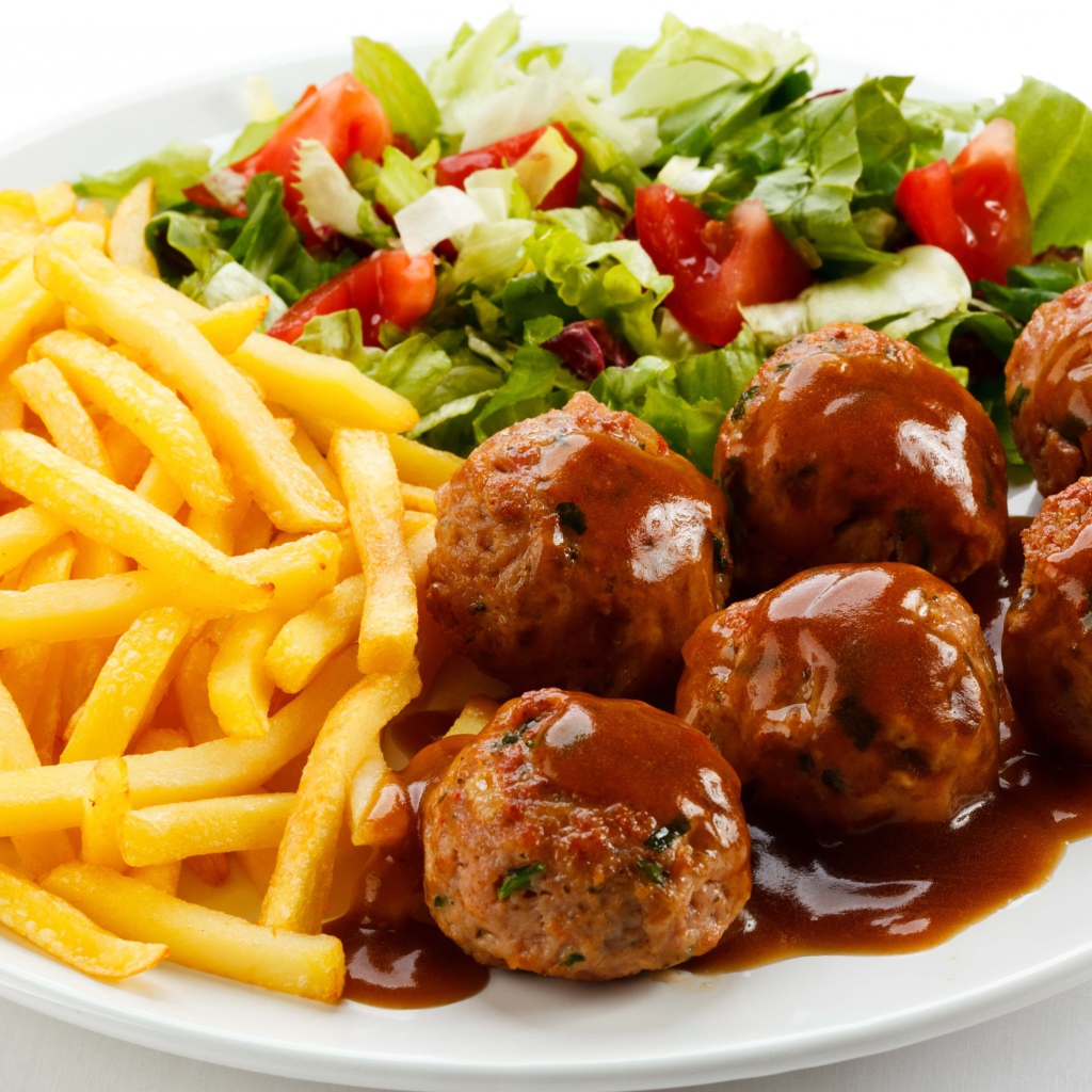 Картофель фри на белой тарелке с салатом и фрикадельками