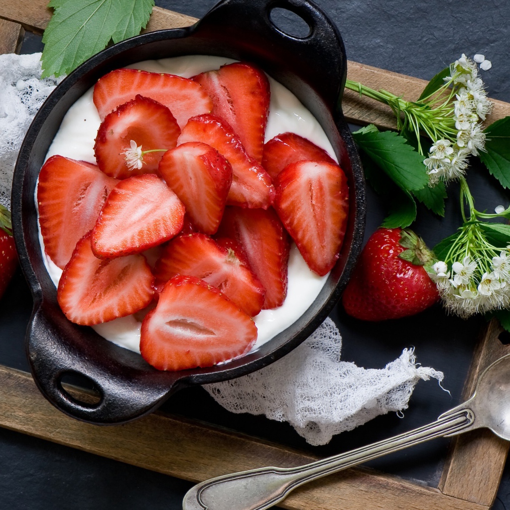 Свежая клубника с йогуртом на завтрак на столе с белым цветком
