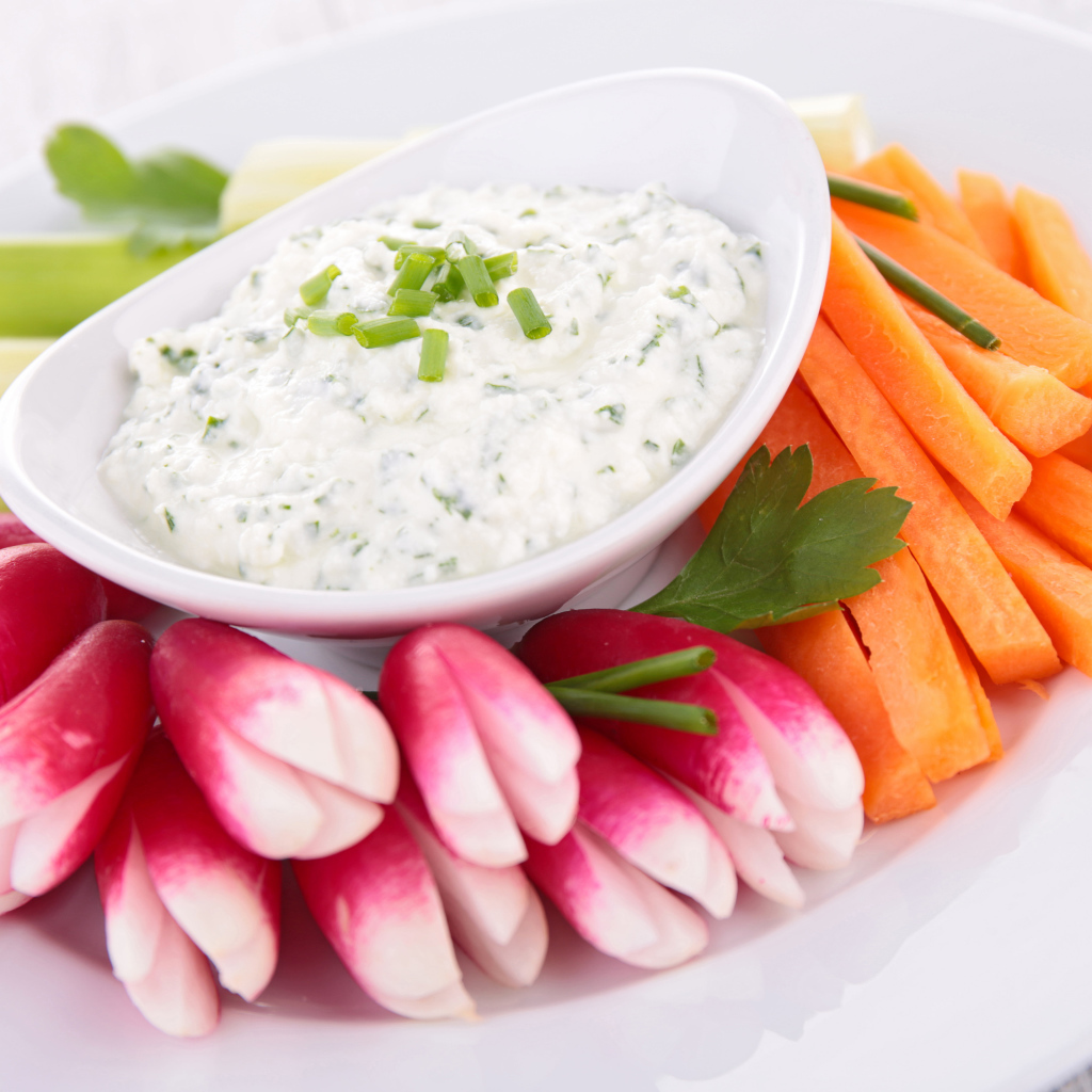 Свежие овощи с соусом в белой тарелке 