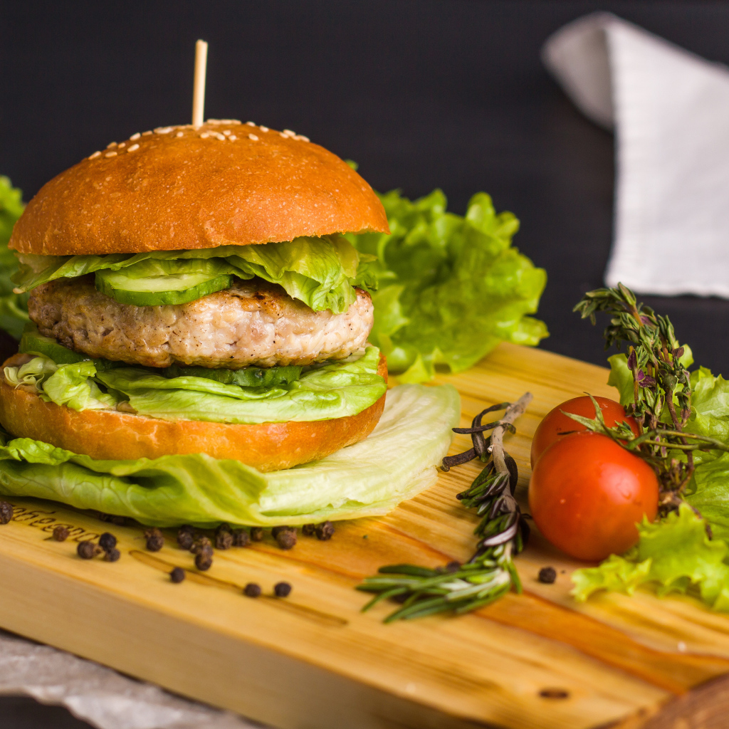 Гамбургер с зеленью на разделочной доске  