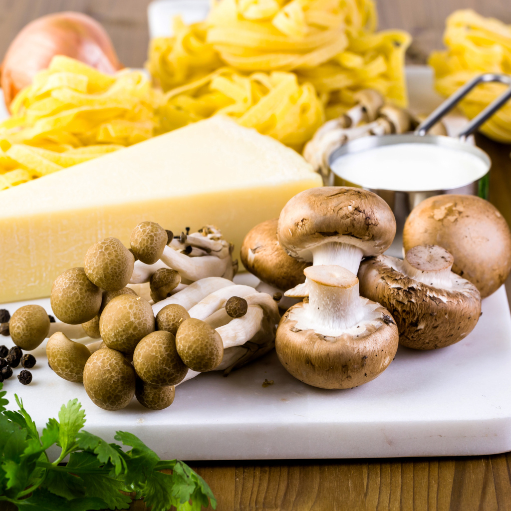 Грибы на разделочной доске с сыром, макаронами и зеленью