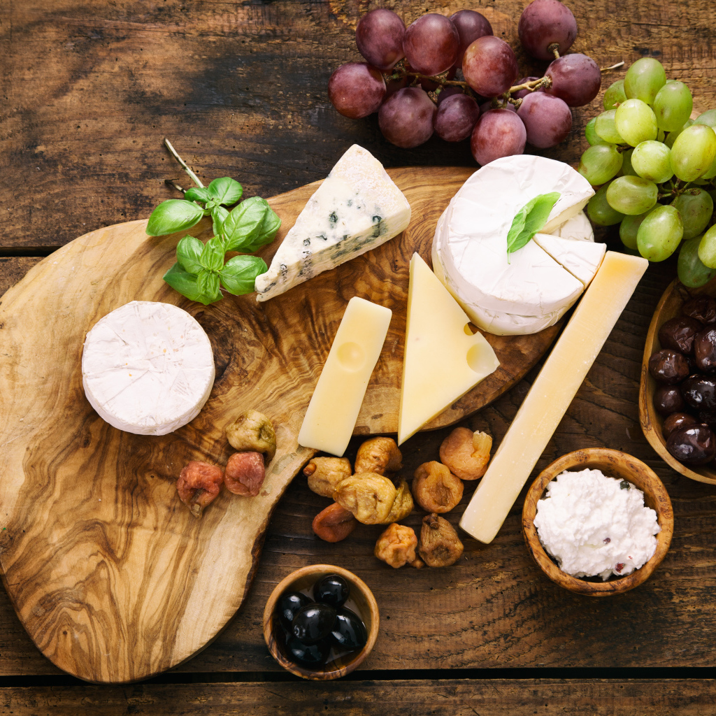 Кусочки сыра с виноградом и оливками на столе