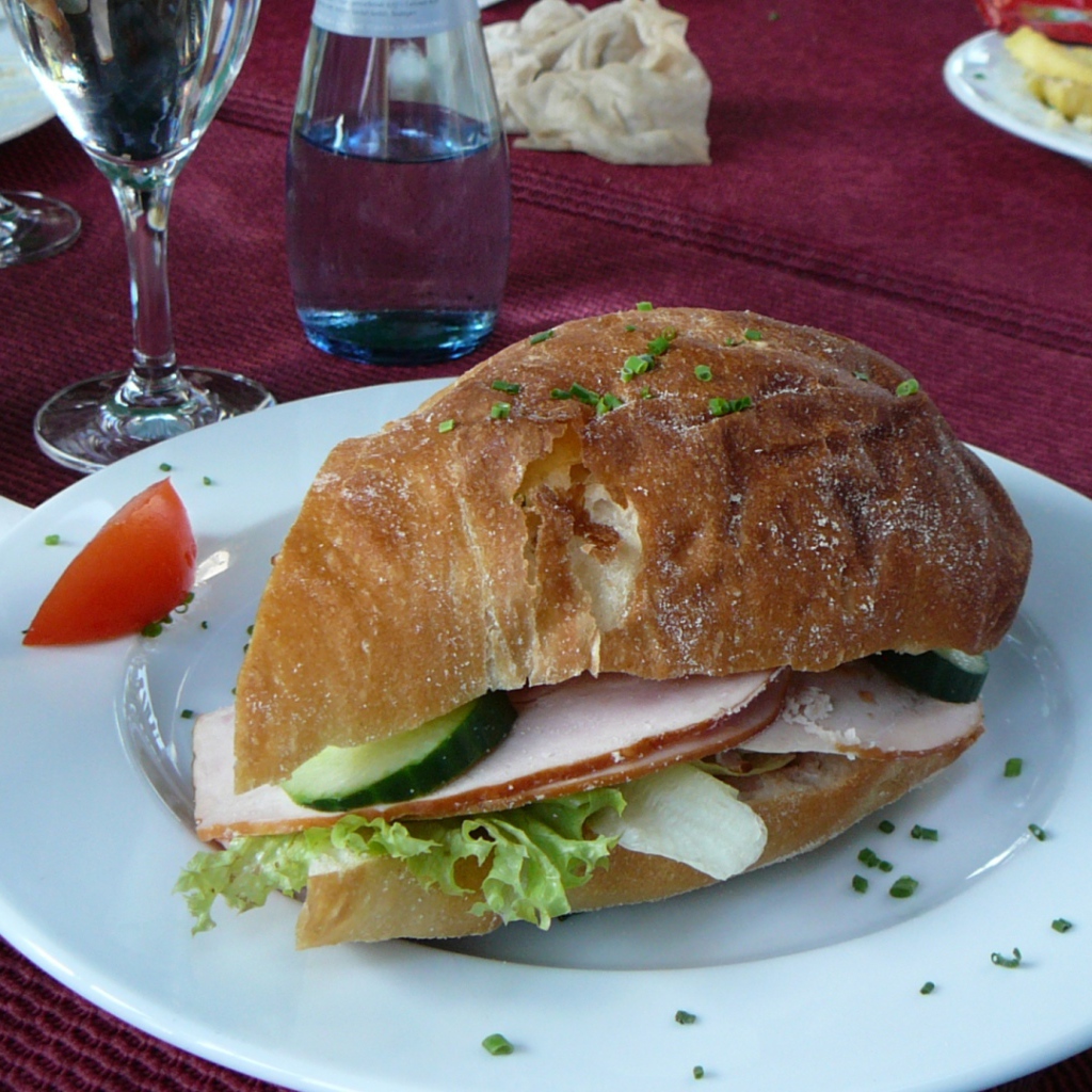 Сэндвич с ветчиной и овощами на столе в ресторане