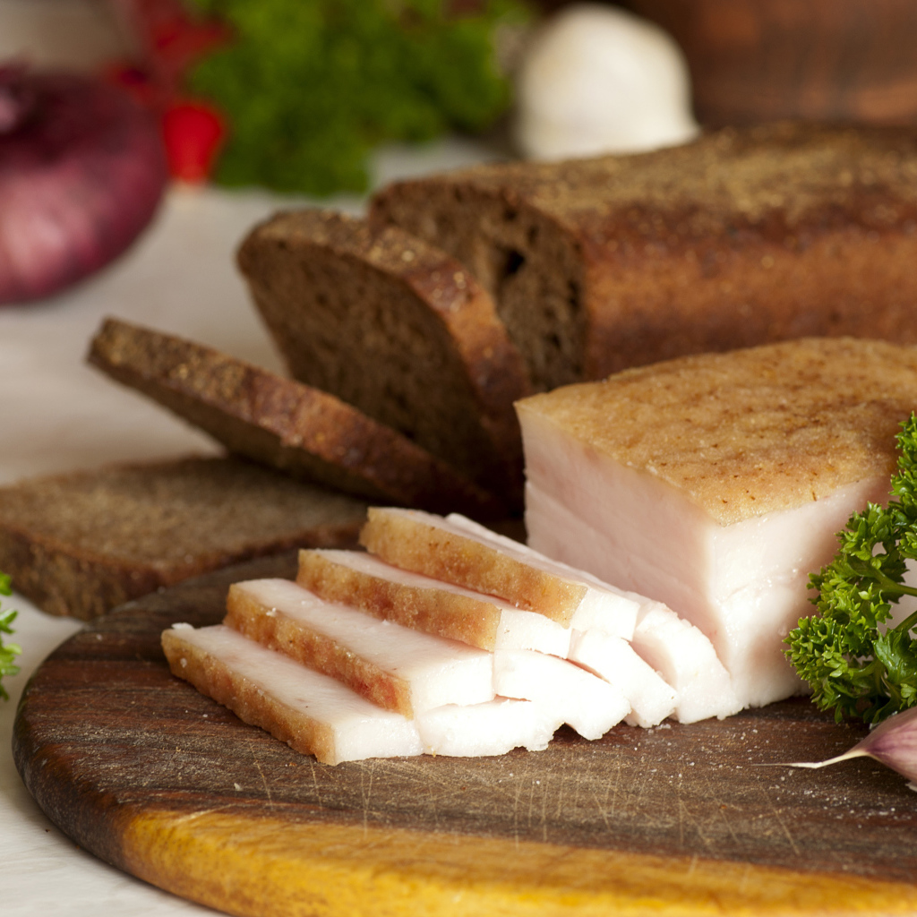 Нарезанное кусочками сало и черный хлеб на разделочной доске