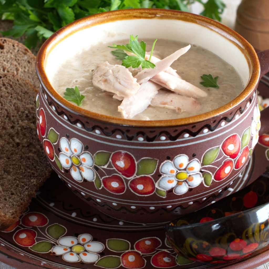 Суп с курицей в красивой тарелке на столе с черным хлебом