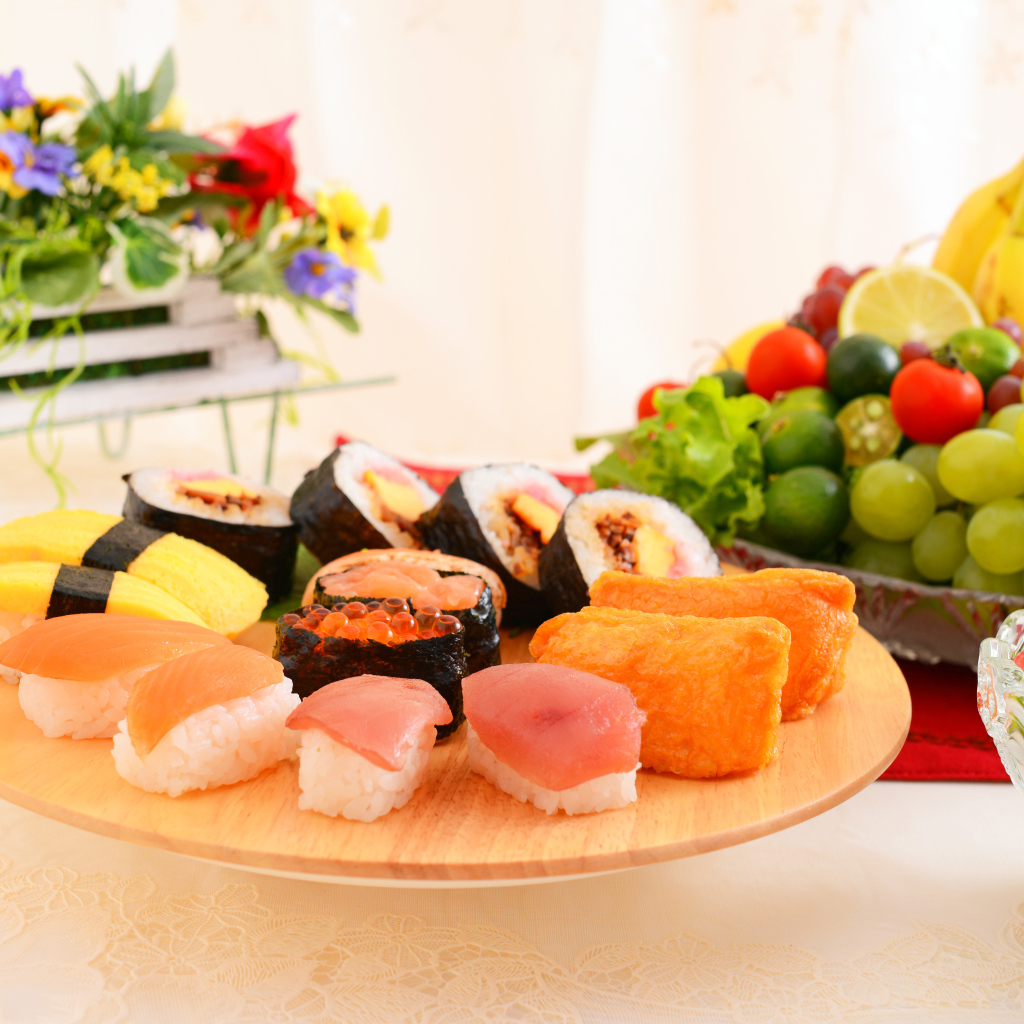 Суши на столе с фруктами и салатом из овощей