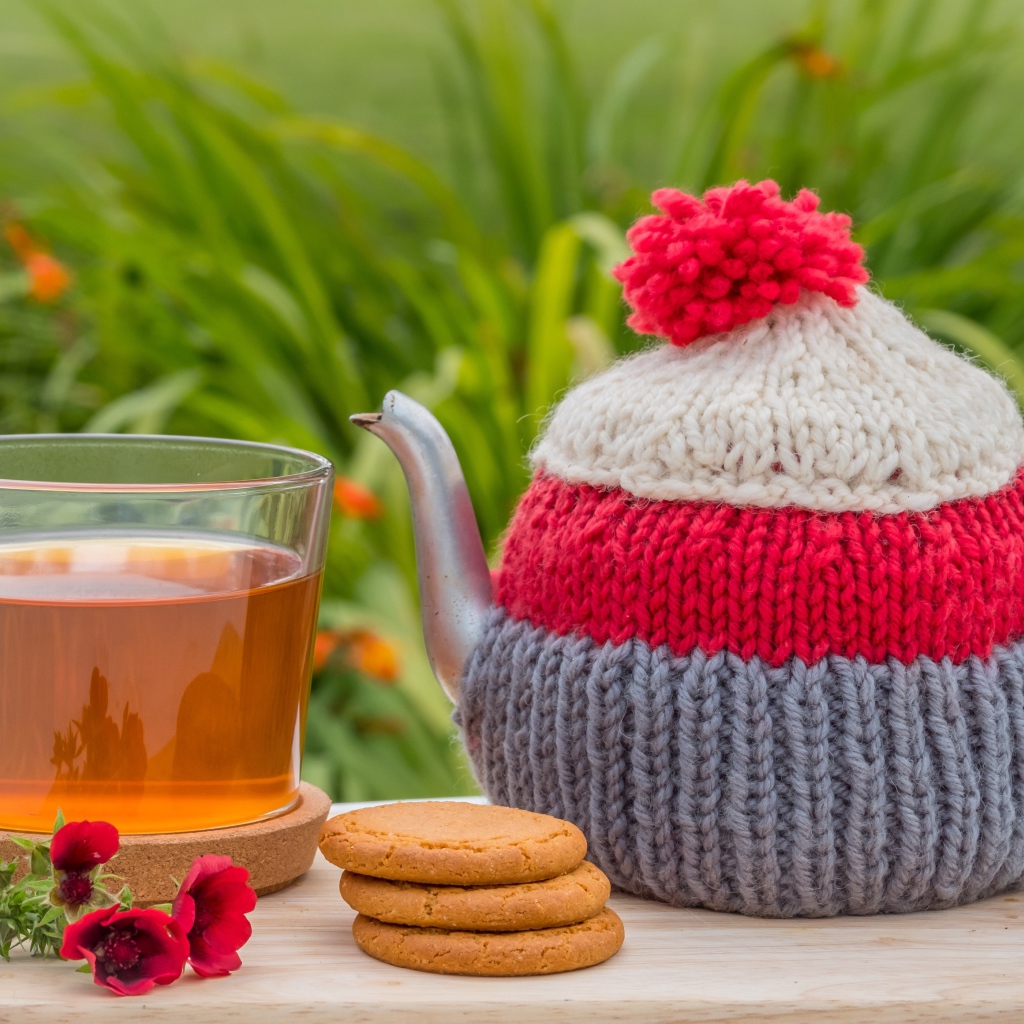 Чайник с чашкой чая на столе с печеньем и цветами