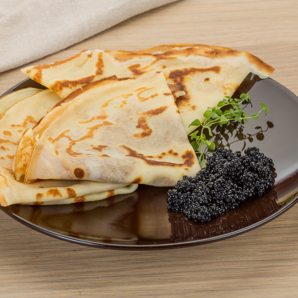 Thin pancakes on a plate with black caviar