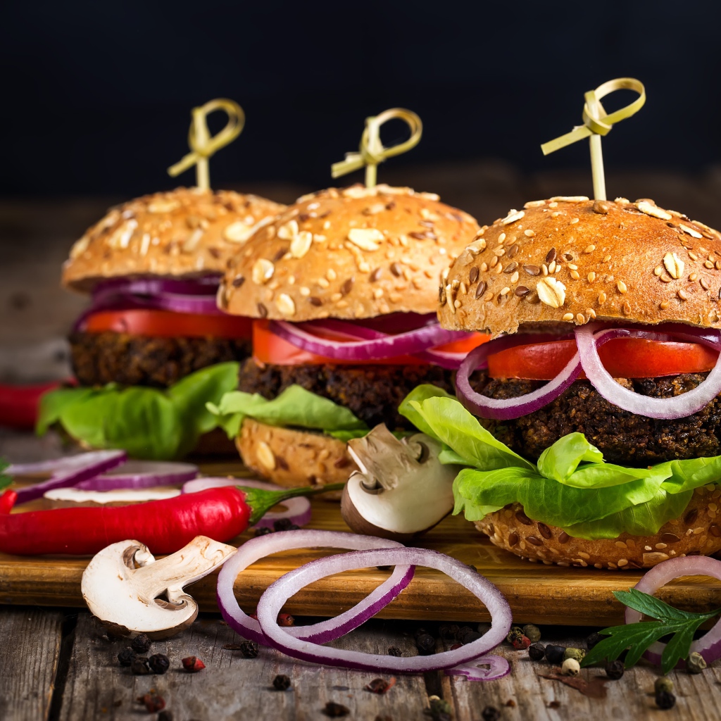 Три аппетитных гамбургера с кольцами лука и перцем