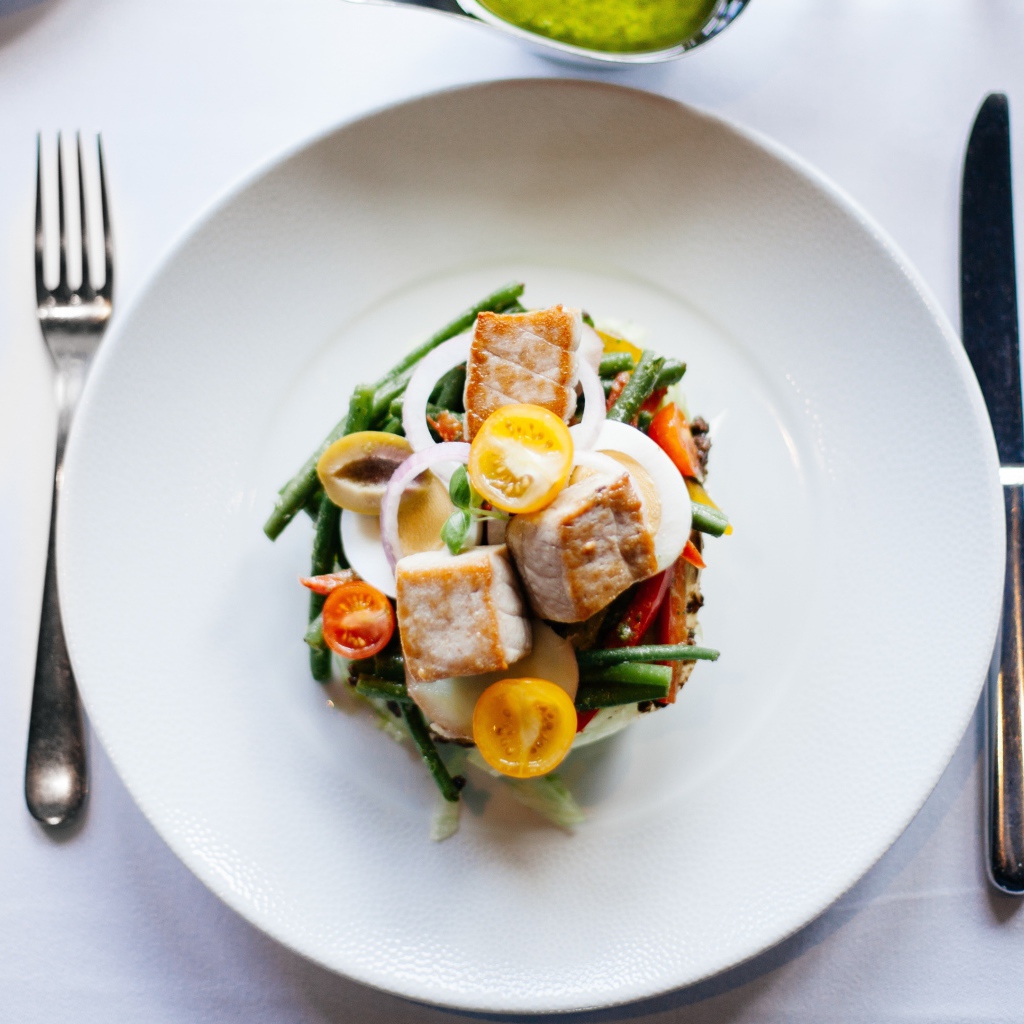 Овощной салат на белой тарелке со столовыми приборами