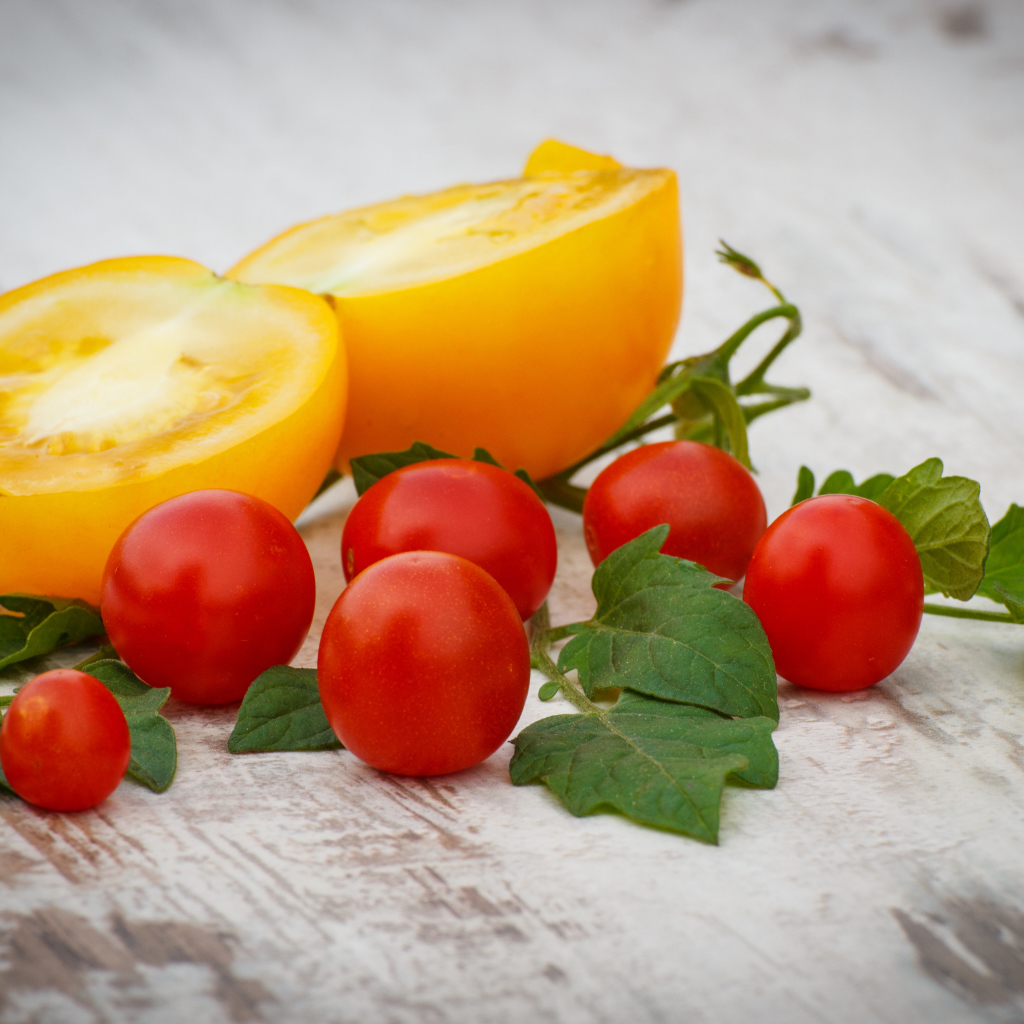 Желтые и красные помидоры на деревянной доске