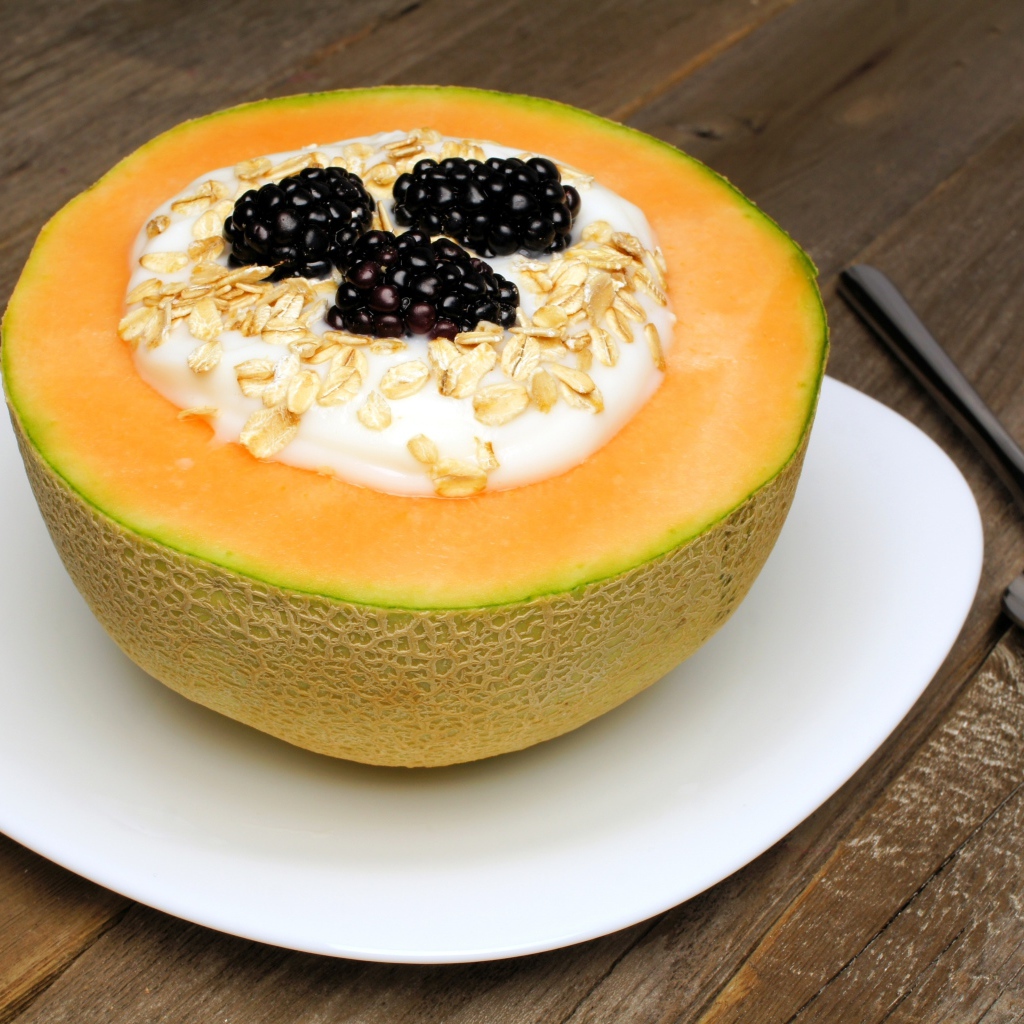 Йогурт с ежевикой и овсянкой в тарелке из свежей дыни на завтрак