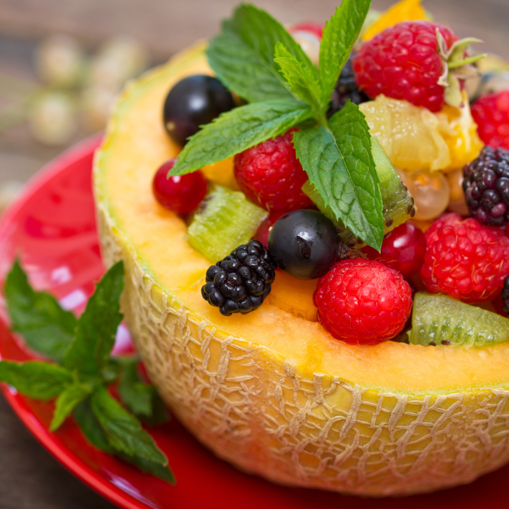 Аппетитные свежие ягоды с листьями мяты в половине дыни