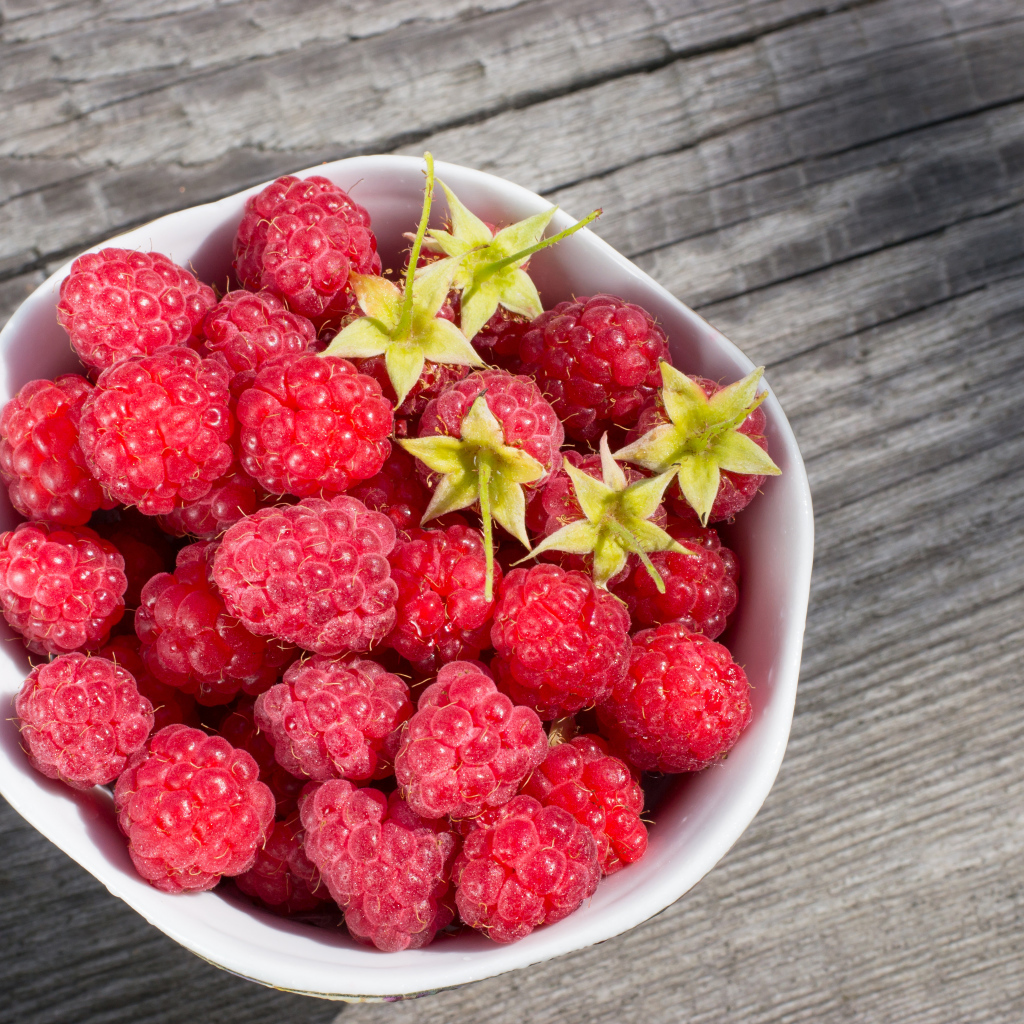 Аппетитная сочная свежая малина в белой тарелке 