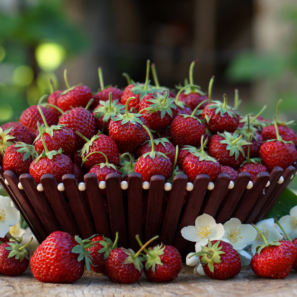 Ягоды спелой свежей клубники с цветами на столе