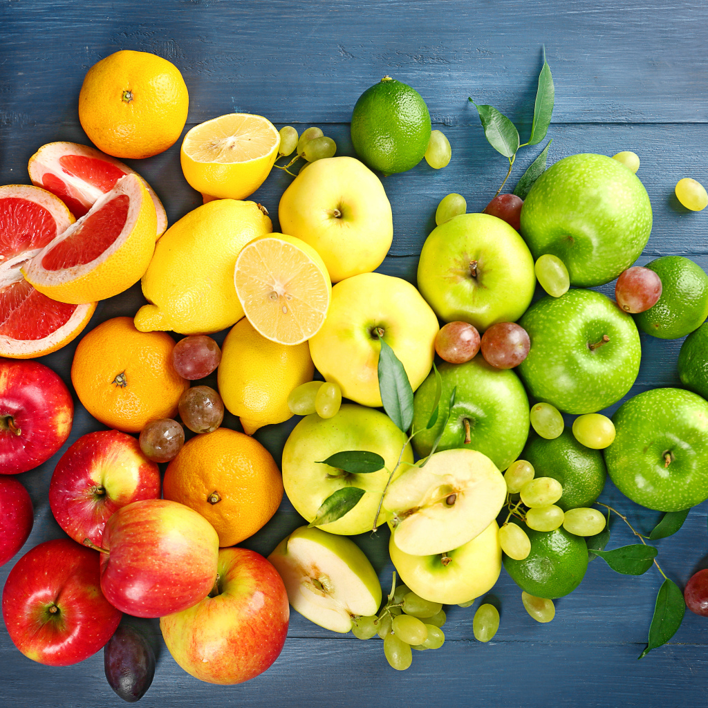 Свежие яблоки, авокадо, лимоны, мандарины и  виноград на столе