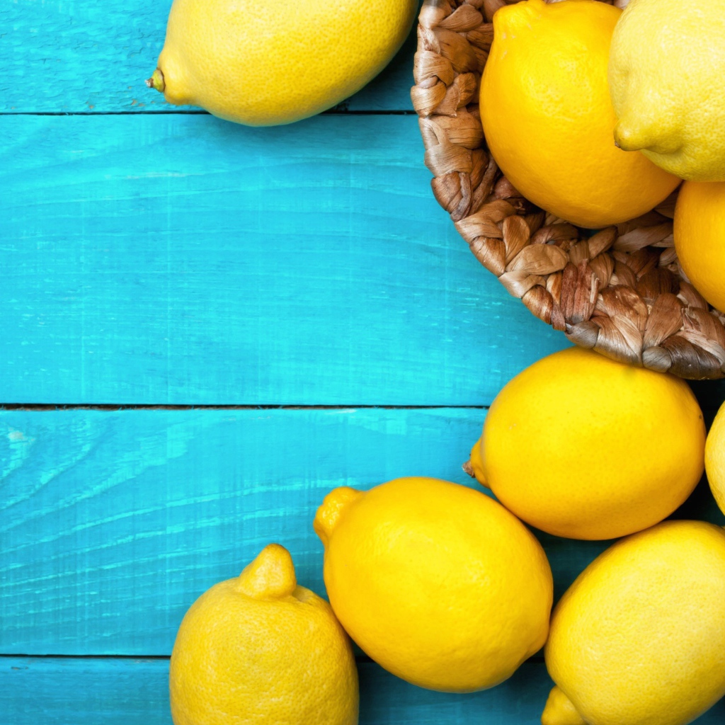 Свежие желтые лимоны лежат на голубой поверхности стола